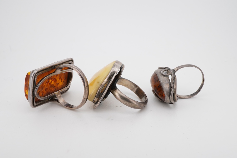 A collection of silver and amber jewels, comprising: two pairs of pendent earrings, three rings and a pendant necklace, all set with amber, mounted in silver; together with a silver and tiger's eye pendant necklace